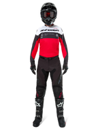 Pilota di motocross con maglia Alpinestars Pro-Dura in nero, rosso vivace e bianco, abbinata a pantaloni neri, stivali neri e casco nero, equipaggiamento completo da gara fuoristrada.