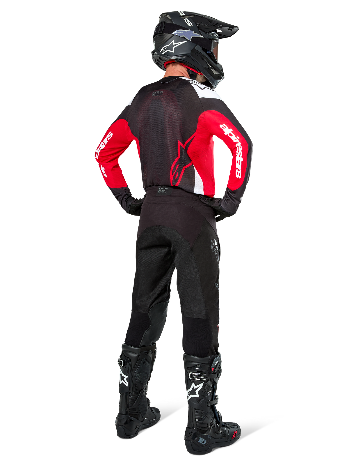 Pilota di motocross visto da dietro con maglia Alpinestars Pro-Dura in nero, rosso acceso e bianco, abbinata a pantaloni, casco e stivali neri, mostra il design posteriore e i loghi sulle maniche, abbigliamento coordinato per corse off-road.
