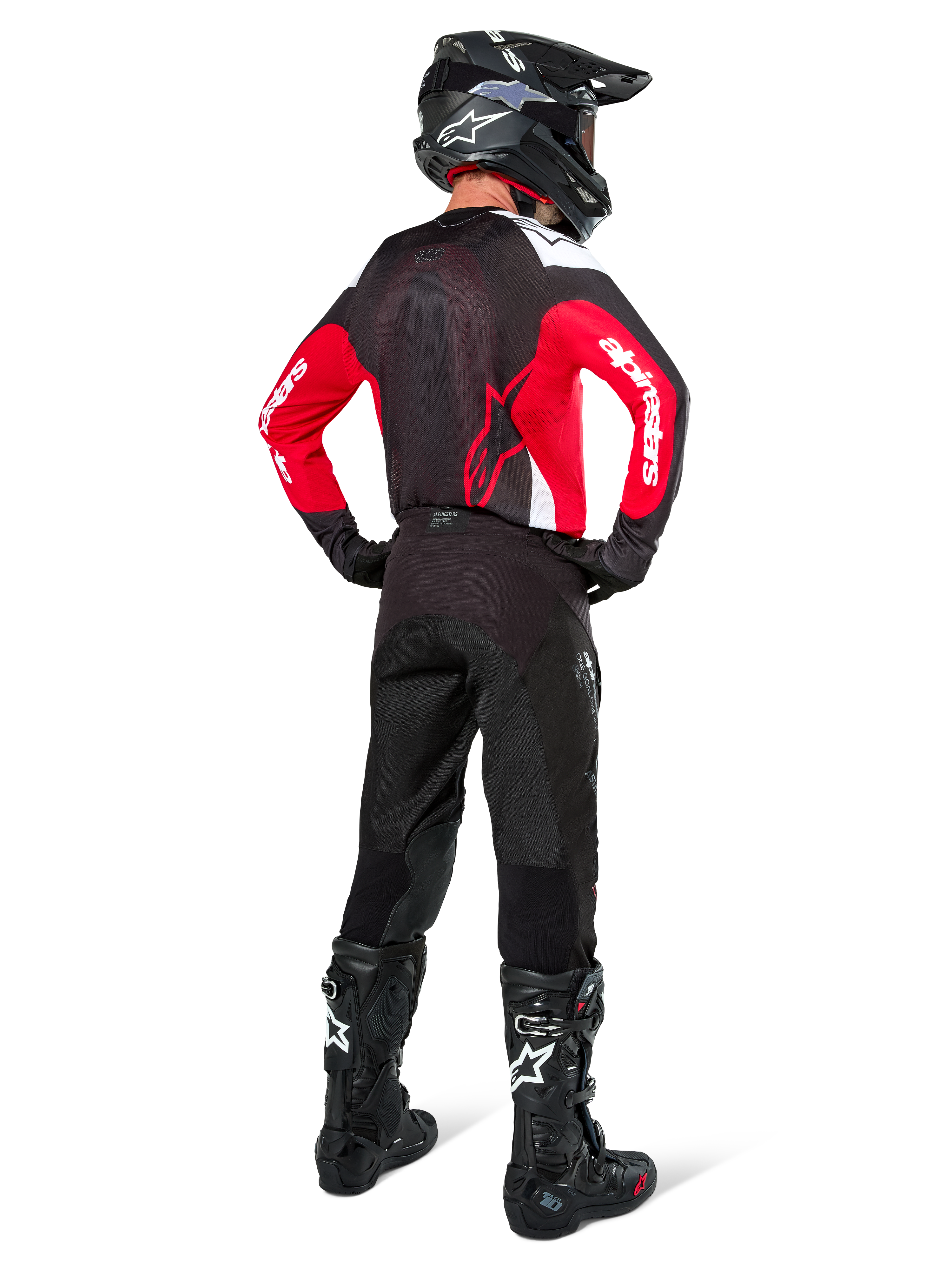 Pilota di motocross visto da dietro con maglia Alpinestars Pro-Dura in nero, rosso acceso e bianco, abbinata a pantaloni, casco e stivali neri, mostra il design posteriore e i loghi sulle maniche, abbigliamento coordinato per corse off-road.