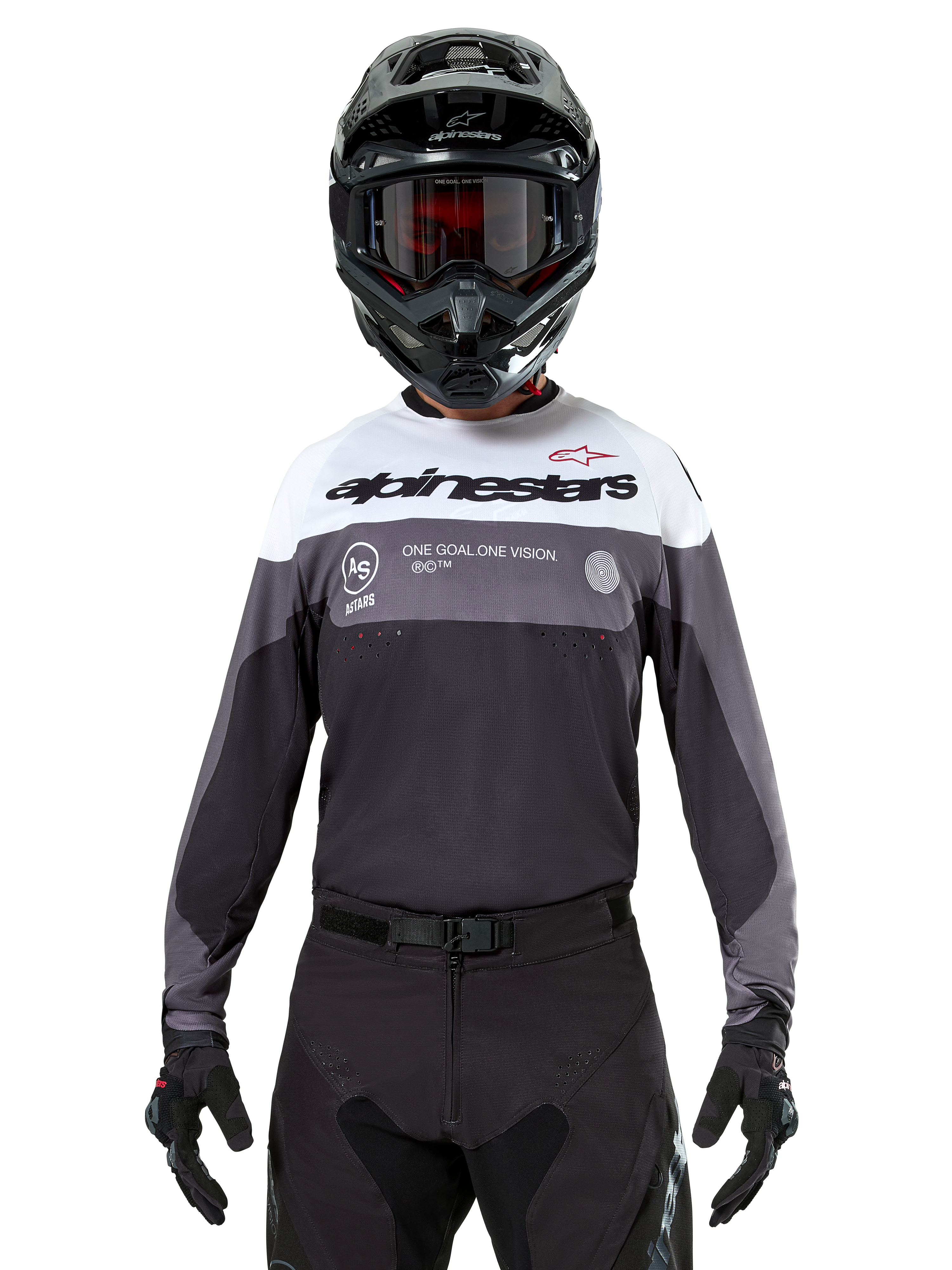 Pilota di motocross con maglia Alpinestars Pro-Dura in Black Magnet White, maglia tecnica a maniche lunghe con inserti bianchi e grigi, indossata con casco e occhiali neri, con logo 'alpinestars' e slogan 'ONE GOAL ONE VISION', abbigliamento da moto off-road