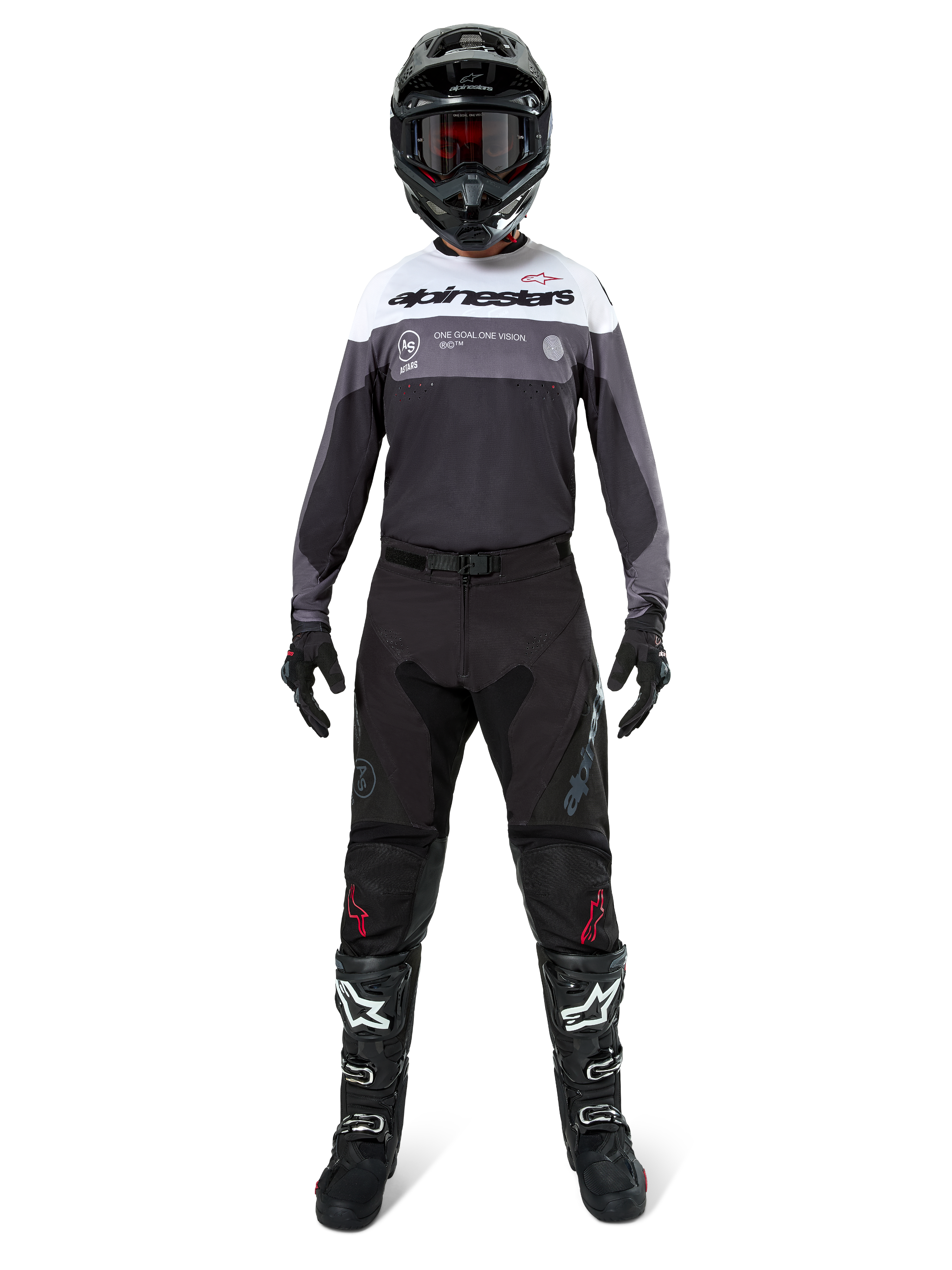 Pilota di motocross con equipaggiamento da gara completo, maglia Pro-Dura in Black Magnet White con parte superiore del petto bianca e dettagli grigi, abbinata a pantaloni neri, casco nero con maschera scura, stivali bianchi e neri e guanti neri, outfit coordinato per enduro e fuoristrada