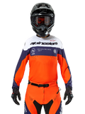 Maglia Alpinestars Pro-Dura, maglia da motocross, blu navy, arancione acceso e bianco, indossata con casco e guanti neri, con zone di ventilazione traforate al laser, branding audace e grafica sul petto "ONE GOAL. ONE VISION."