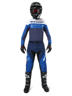 Pilota di motocross con equipaggiamento completo Alpinestars, Maglia Pro-Dura nei colori blu navy, blu brillante e bianco, pantaloni coordinati blu e navy, casco nero con occhiali rossi, stivali neri e bianchi, outfit per enduro e guida off-road