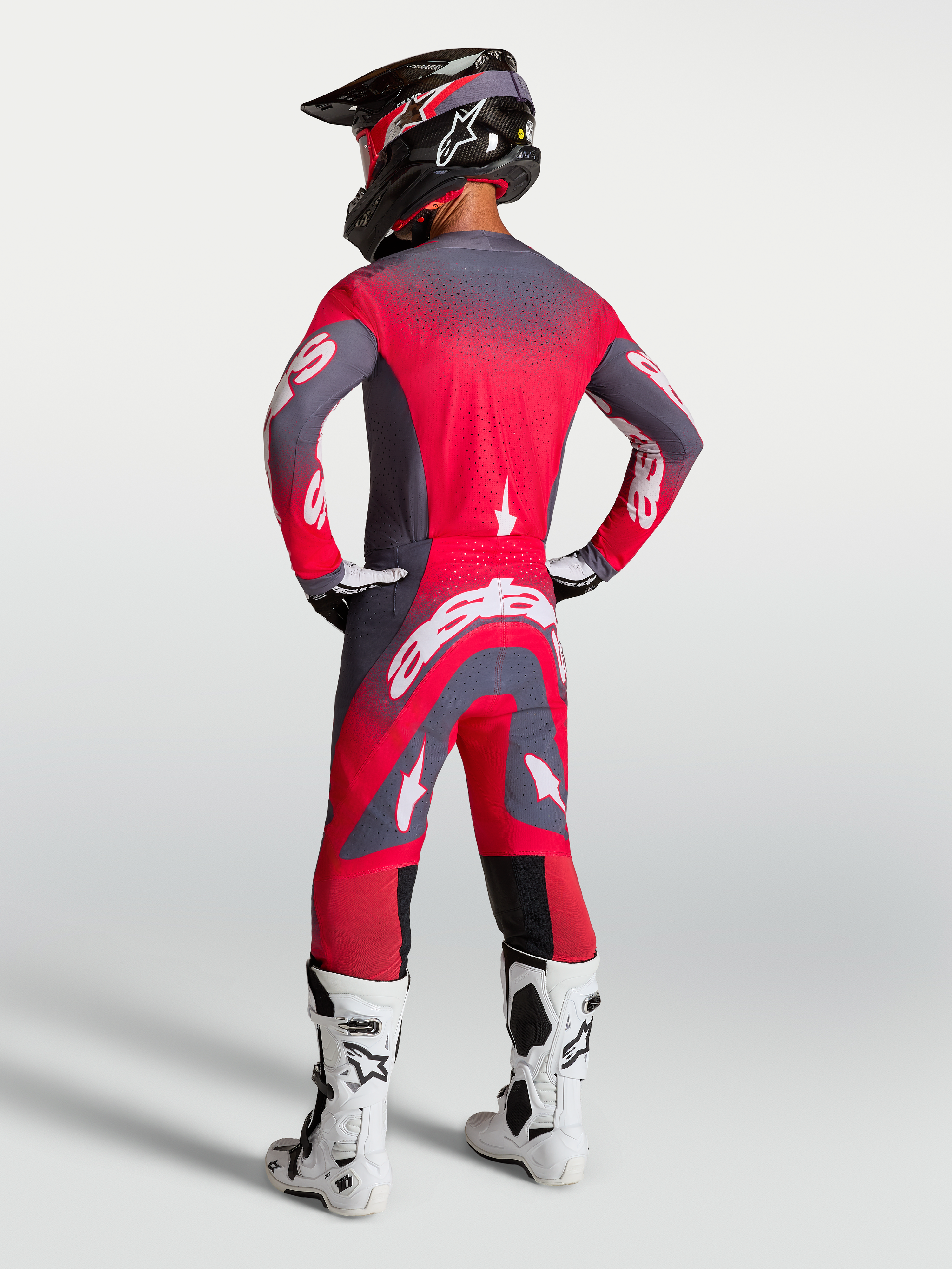 Alpinestars Maglia e Gear Set Supertech Hiten AFD, completo da motocross rosso fluo e grigio, vista posteriore su modello.