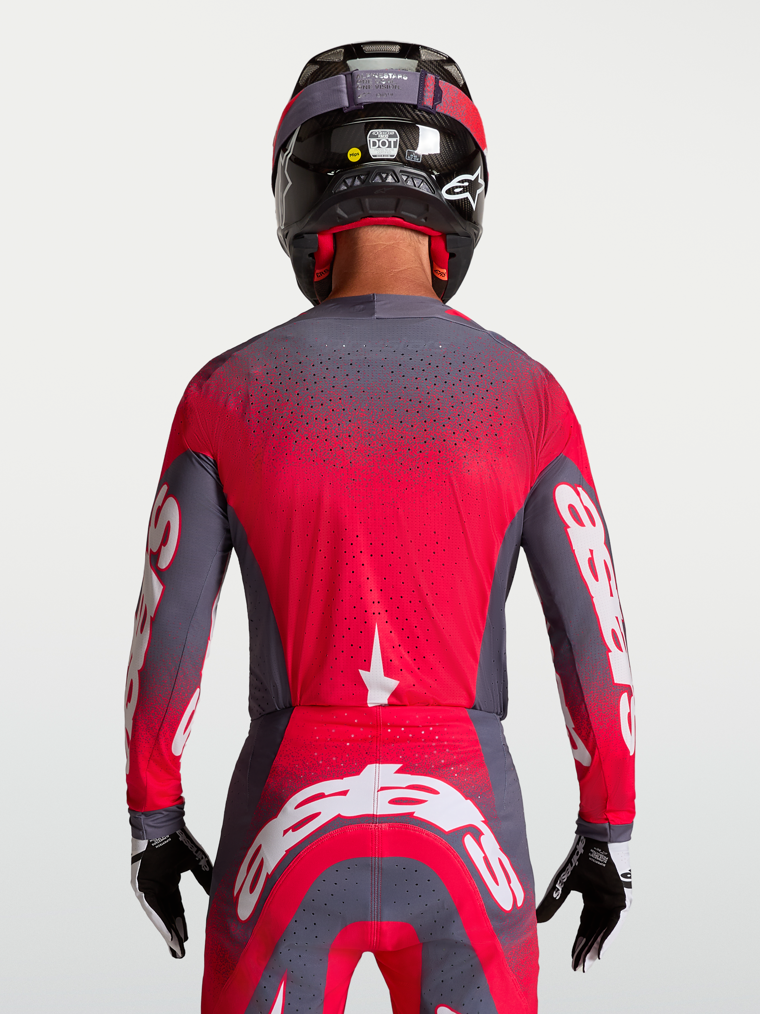 Alpinestars Maglia Supertech Hiten AFD, maglia da motocross per uomo, grigio e rosso fluo, costruzione in mesh ventilato con perforazioni laser-cut per un flusso d'aria ottimale, vista posteriore indossata da un pilota con casco e guanti, abbigliamento racing off-road