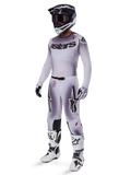 Set completo Alpinestars Supertech Maker 2025, abbigliamento completo da motocross, sfumatura bianca e grigia con branding nero e accenti rossi, include casco con maschera, maglia, pantaloni, stivali bianchi e guanti, design aerodinamico orientato alle prestazioni per gare fuoristrada