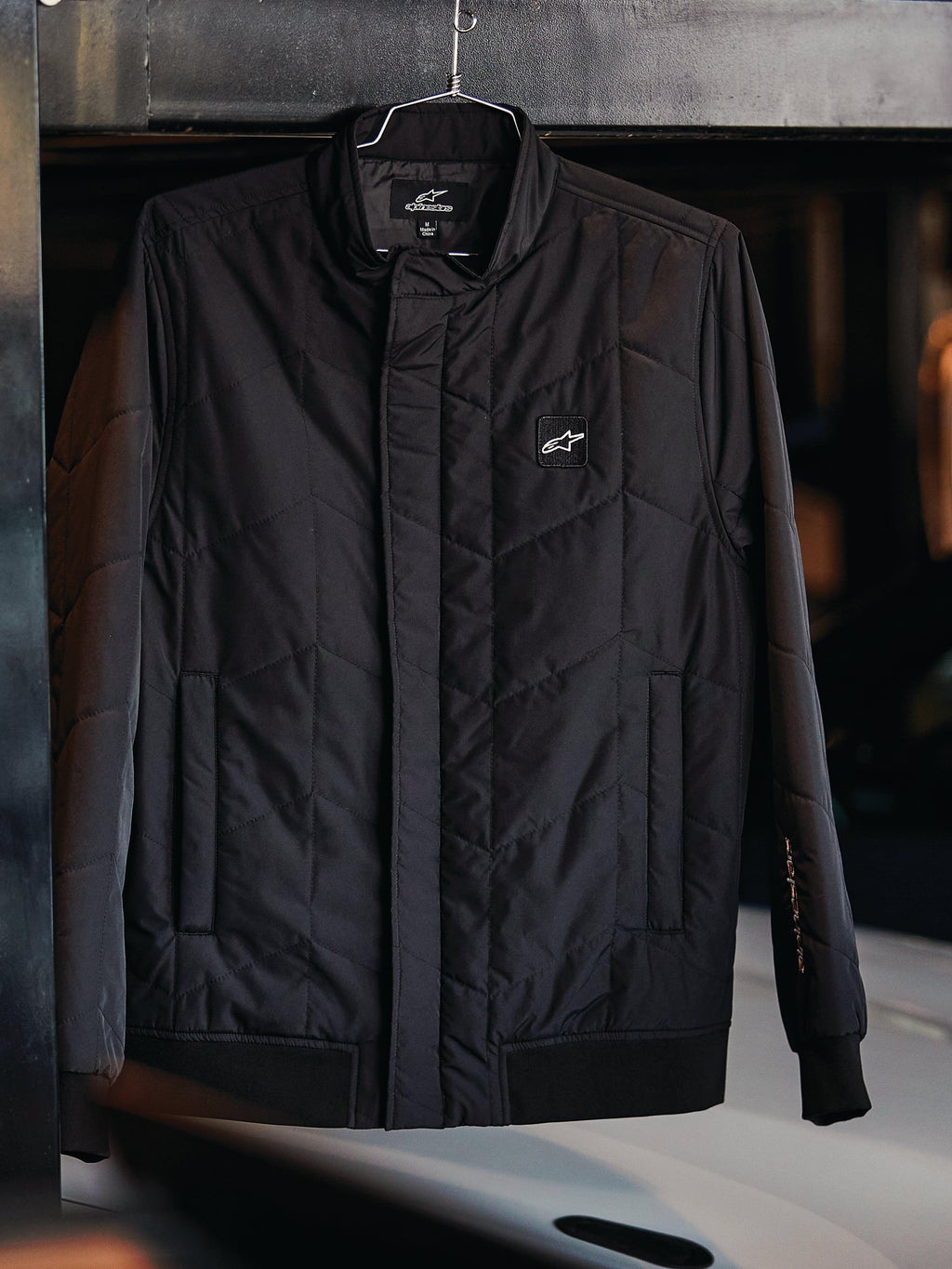 Alpinestars Giacca Precedent, giacca sportiva trapuntata, nero, con motivo trapuntato angolato, colletto basso con cerniera coperta, patch con logo sul petto, polsini e orlo a coste, design ispirato al motorsport
