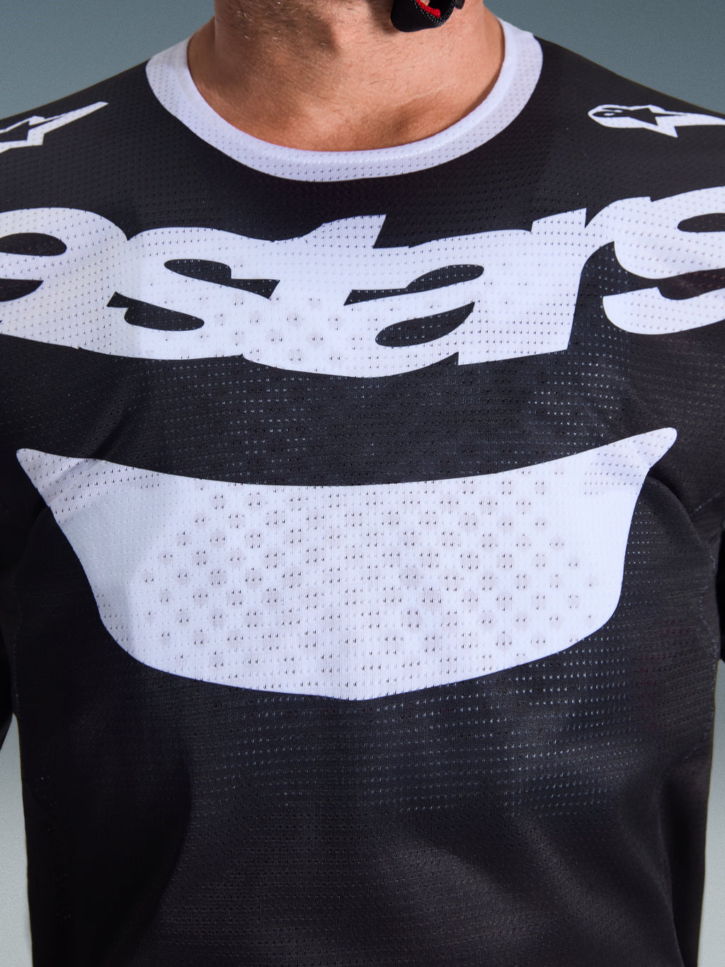 Alpinestars 2026 Racer Air Riway Jersey, maglia da motocross, nero e bianco, primo piano del torace che mostra la grande grafica bianca e la costruzione in mesh traspirante, colletto bianco e loghi sulle spalle