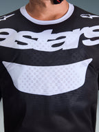 Alpinestars 2026 Racer Air Riway Jersey, maglia da motocross, nero e bianco, primo piano del torace che mostra la grande grafica bianca e la costruzione in mesh traspirante, colletto bianco e loghi sulle spalle