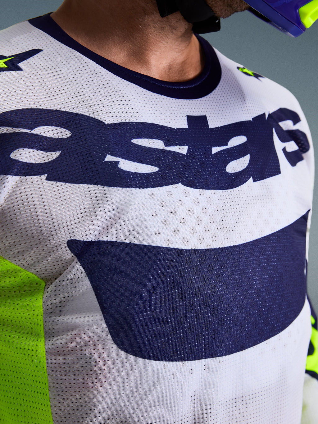 Alpinestars 2026 Racer Air Riway Jersey, maglia da motocross, grigio chiaro, giallo fluo e blu, primo piano del torace con struttura in mesh traspirante e logo Astars blu navy, progettata per la guida off-road ad alte prestazioni.