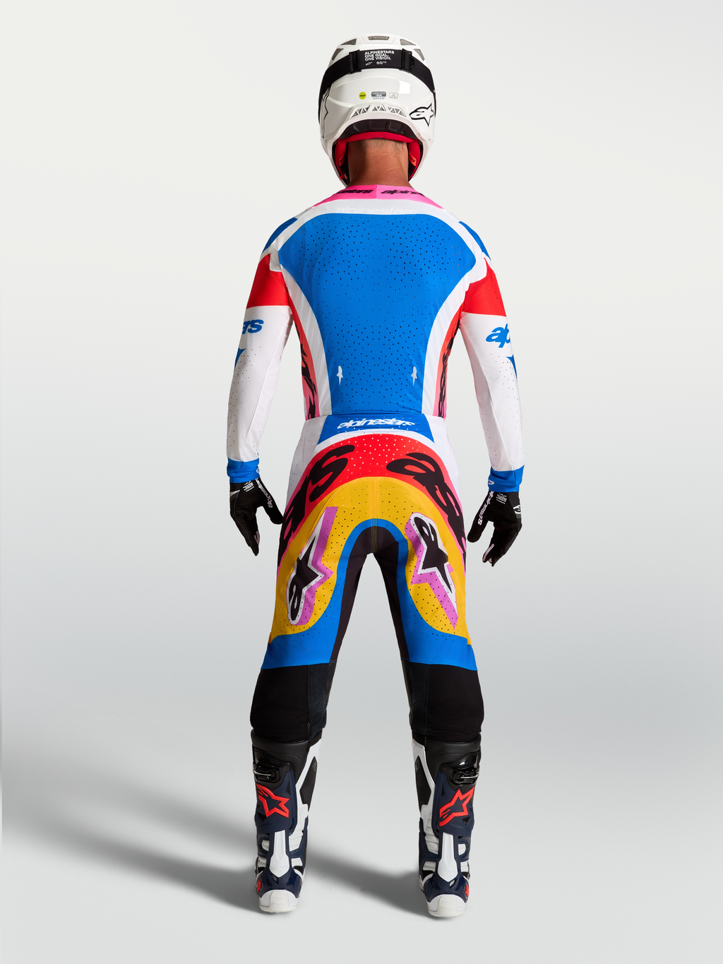Alpinestars maglia Supertech Dyna e completo da motocross blu e bianco con accenti rosa, vista posteriore su modello.