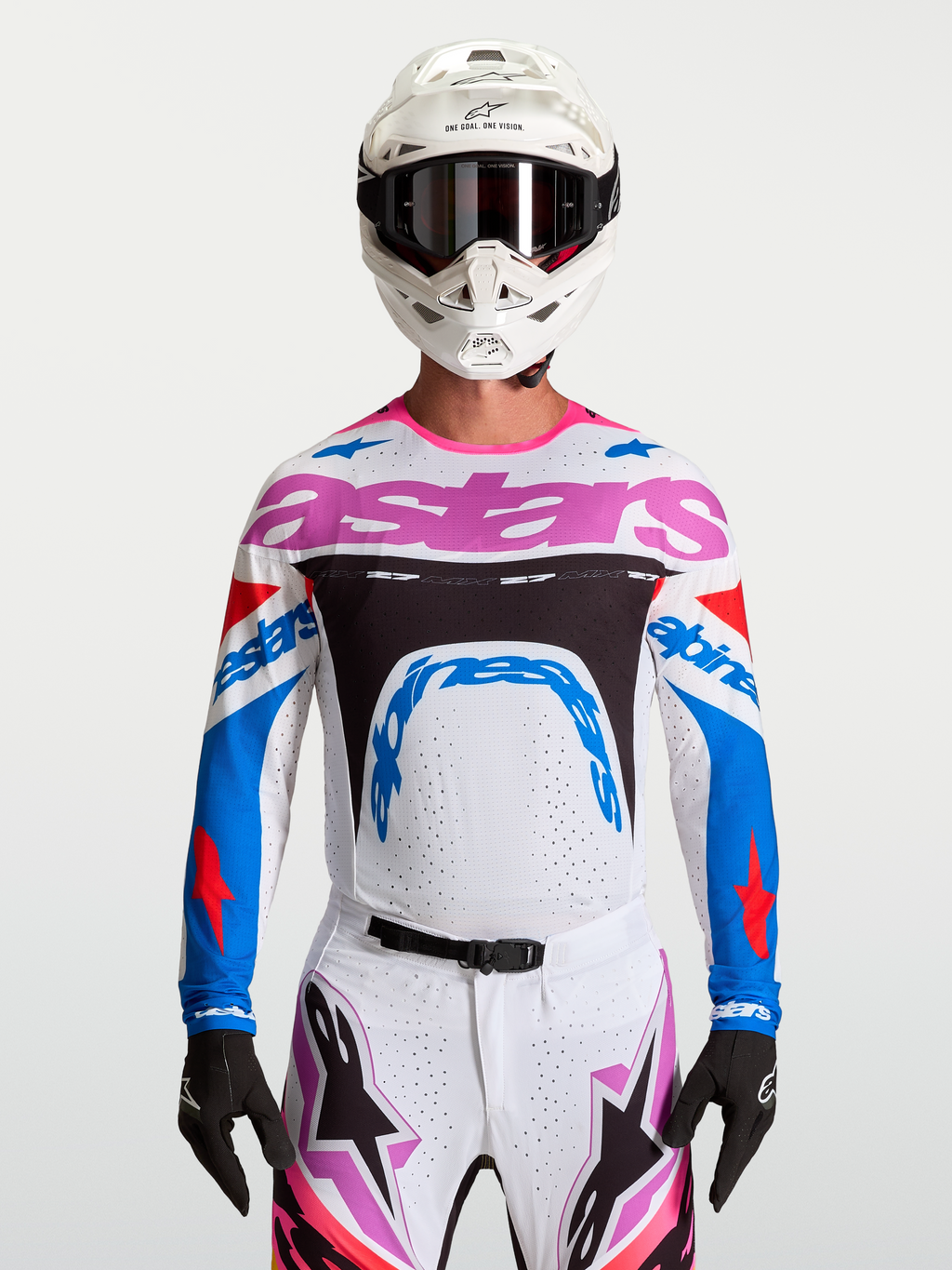 Alpinestars Maglia Supertech Dyna, maglia da motocross da uomo, bianca, blu e rosa, in mesh elasticizzato e traspirante, vestibilità racing per gare MX, indossata da un pilota con casco bianco e guanti neri.