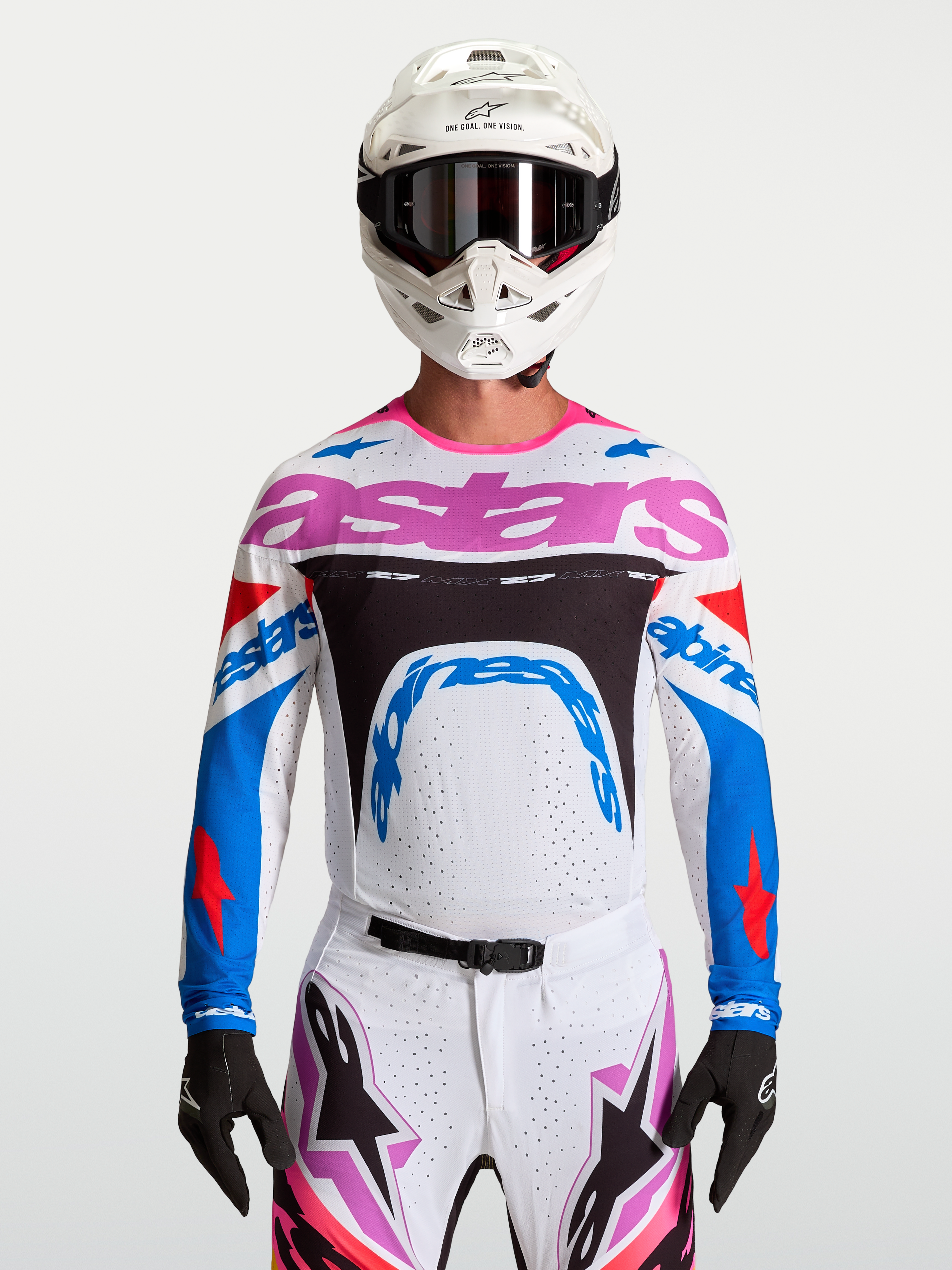 Alpinestars Maglia Supertech Dyna, maglia da motocross da uomo, bianca, blu e rosa, in mesh elasticizzato e traspirante, vestibilità racing per gare MX, indossata da un pilota con casco bianco e guanti neri.