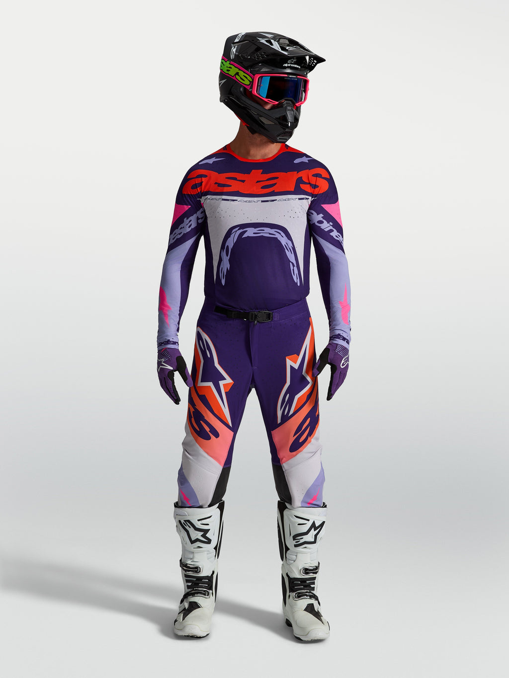 Alpinestars Maglia Supertech Dyna, maglia da motocross racing per uomo, viola e rosa fluo, vestibilità atletica e ultra-leggera, indossata con casco e stivali coordinati per competizioni off-road.