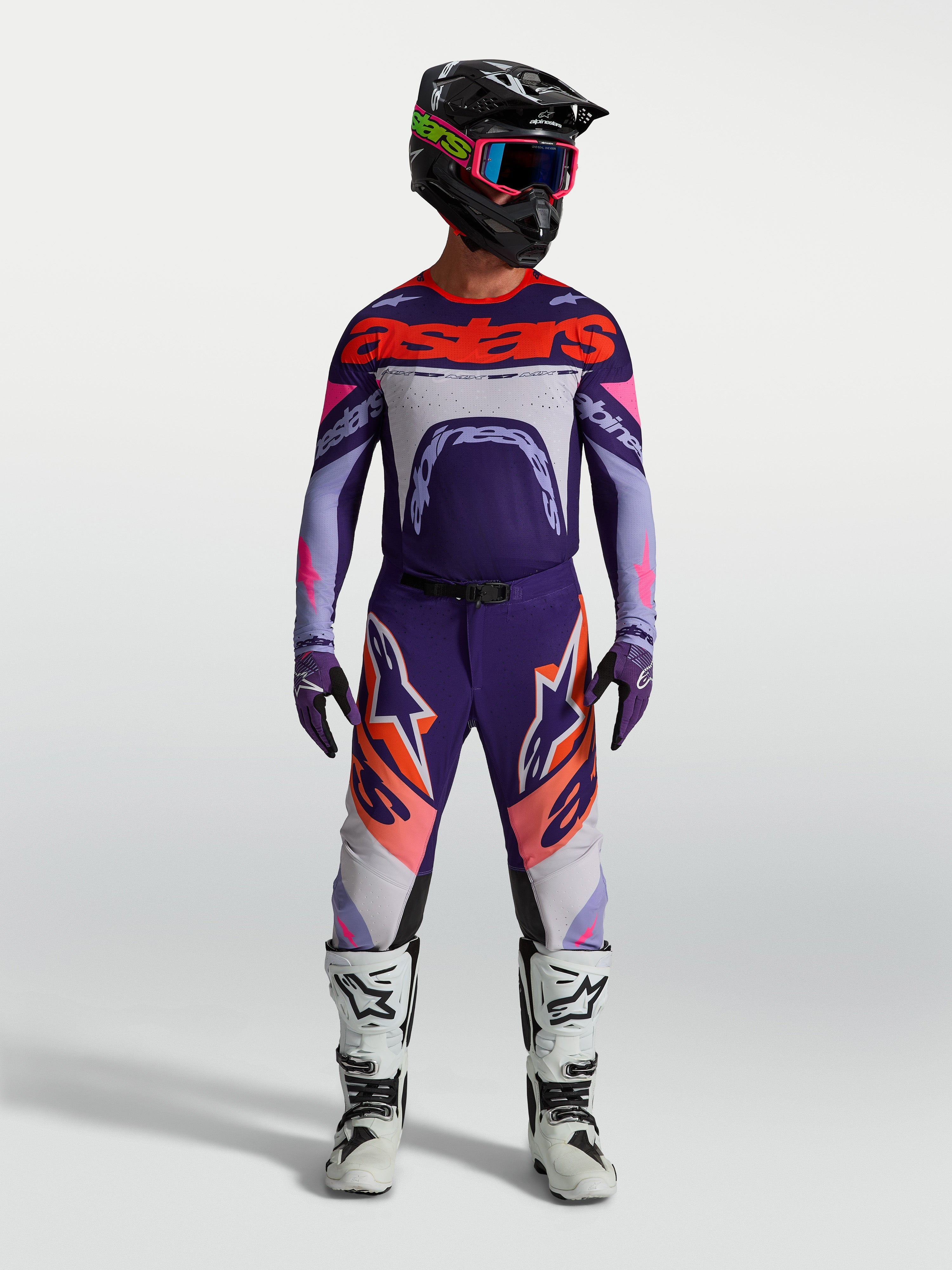Alpinestars Maglia Supertech Dyna, maglia da motocross racing per uomo, viola e rosa fluo, vestibilità atletica e ultra-leggera, indossata con casco e stivali coordinati per competizioni off-road.