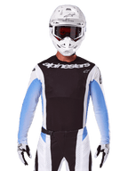 Maglia Alpinestars Techstar Melt 2025, abbigliamento da motocross, nero, bianco e blu, maglia a maniche lunghe con pantaloni e guanti abbinati, pilota che indossa un completo da MX con casco bianco e maschera