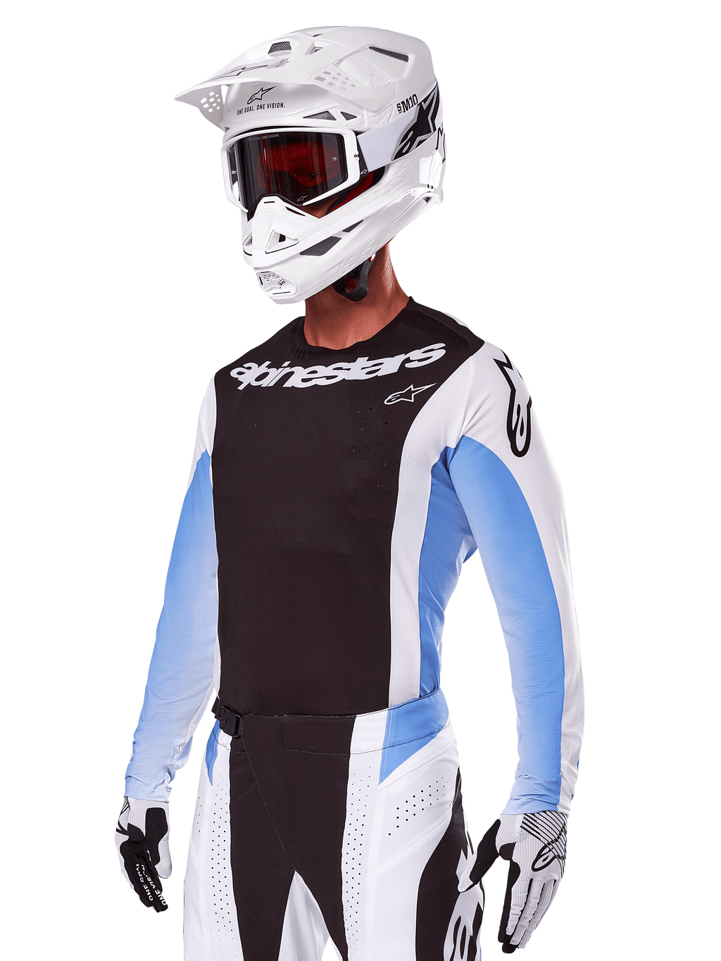 Pilota di motocross con Set Gear Alpinestars Techstar Melt 2025, bianco con dettagli neri e azzurri, maglia con petto nero e maniche bianche, pantaloni coordinati bianchi e neri, casco SM10 bianco con occhiali e guanti bianchi e neri, completo professionale per corse fuoristrada.