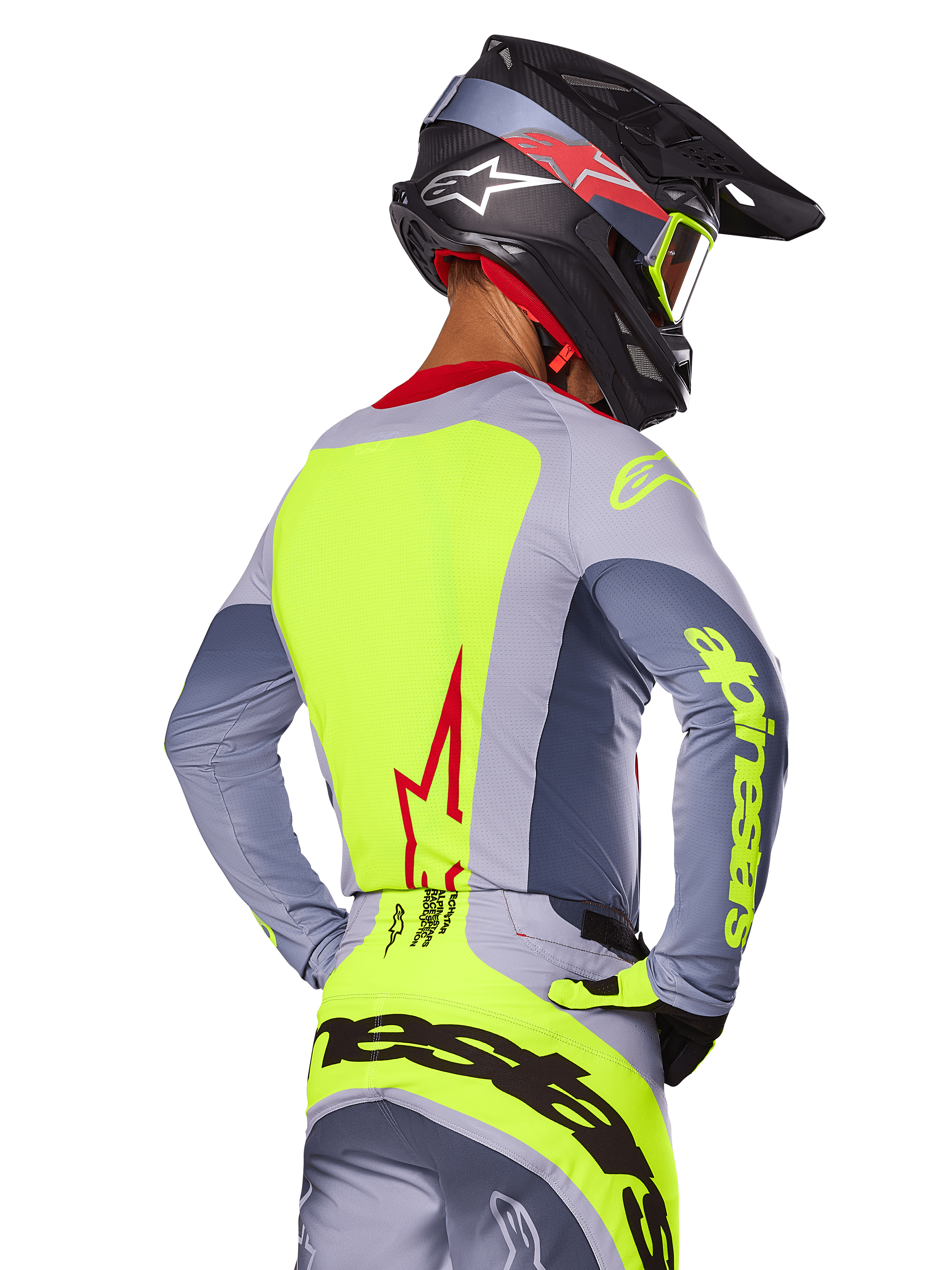 Alpinestars 2025 Techstar Melt Jersey, Bright Red Gray, vista posteriore di un pilota di motocross con abbigliamento da gara grigio e giallo neon, logo a stella rossa sulla schiena, casco coordinato nero e rosso, abbigliamento tecnico per fuoristrada