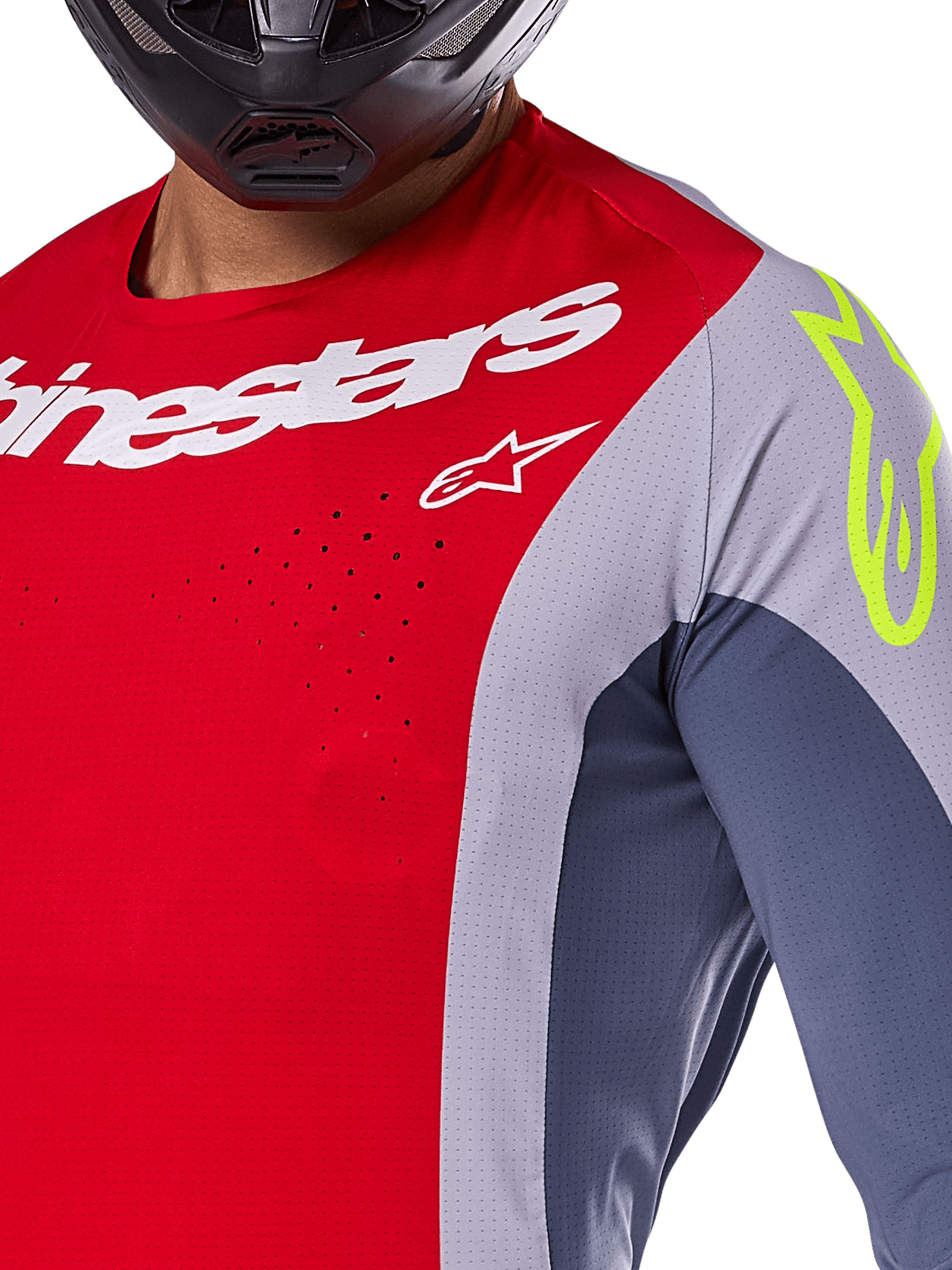 Maglia Alpinestars Techstar Melt 2025, maglia da motocross, rosso acceso e grigio con pannelli blu scuro, con marchio Alpinestars bianco e logo giallo neon sulla spalla, primo piano con perforazioni laser per la ventilazione e casco nero.