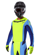 Set Gear Alpinestars Techstar Melt 2025, pilota di motocross con maglia giallo brillante e blu e pantaloni coordinati, casco nero con occhiali bianchi e neri, guanti gialli, abbigliamento da corsa off-road con logo Alpinestars e dettagli traforati