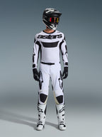 Alpinestars 2026 Racer Riway Jersey, maglia da motocross, bianco e nero, indossata come kit da gara completo con pantaloni coordinati, casco nero con occhiali rossi, guanti neri e stivali bianchi, caratterizzata dal vistoso marchio 'astars' nero e dai loghi a stella.