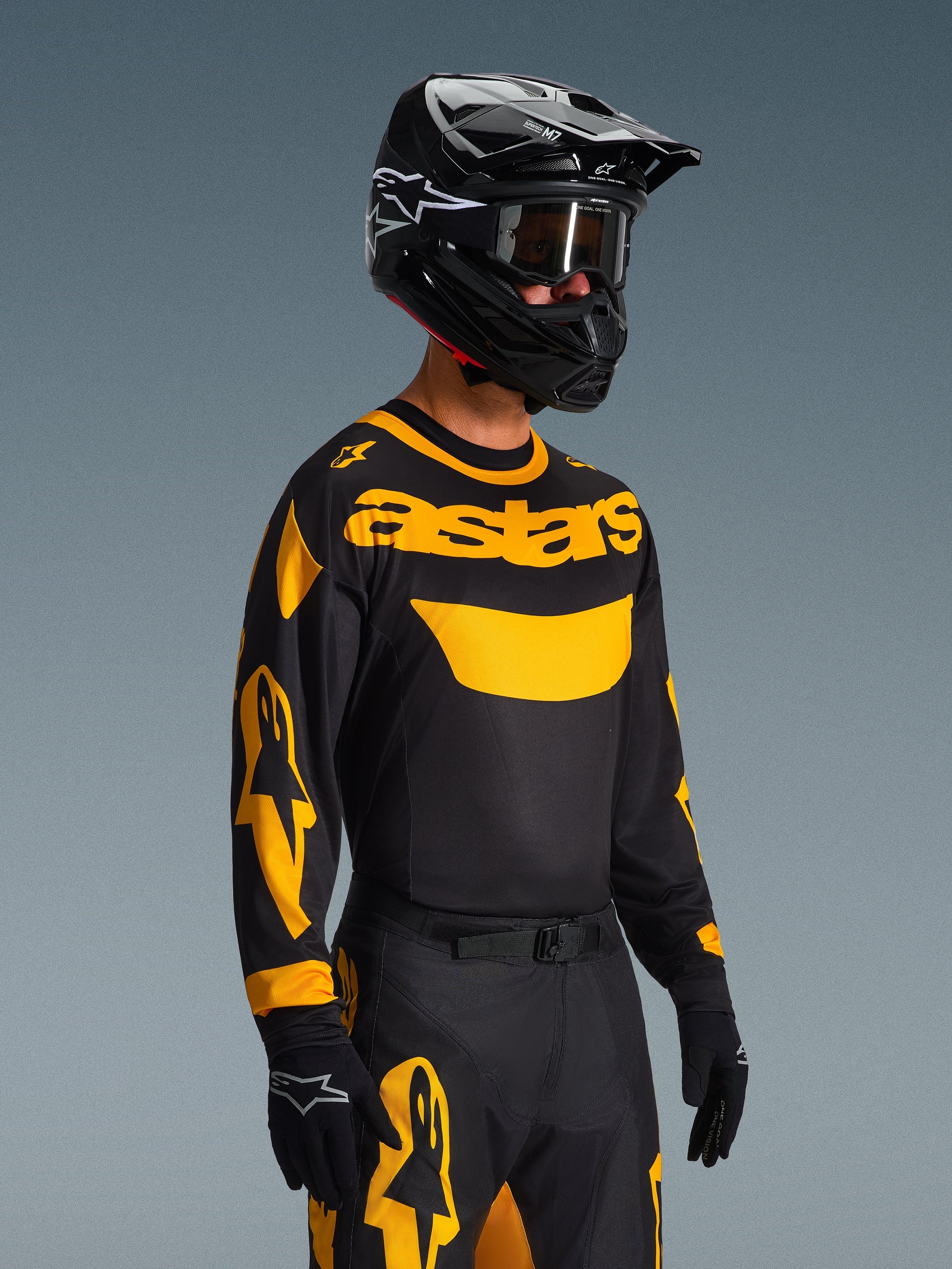 Set Gear Alpinestars Racer Riway 2026, pilota di motocross con maglia nera e marchio 'astars' giallo, pantaloni coordinati neri e gialli, casco nero con occhiali e guanti neri, abbigliamento completo da gara fuoristrada