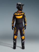 Pilota di motocross che indossa la Maglia Racer Riway 2026 in giallo e nero, coordinata con pantaloni abbinati, casco nero e stivali neri con loghi Alpinestars bianchi, abbigliamento completo per corse off-road.