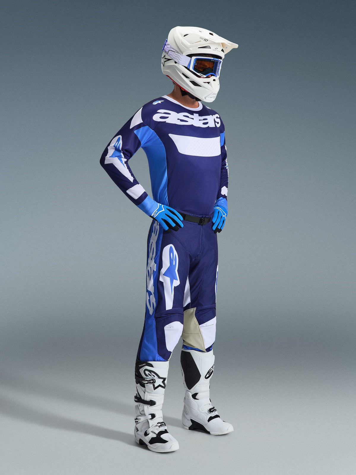 Maglia Alpinestars Racer Riway 2026 in blu Ucla e bianco, indossata da un pilota di motocross con pantaloni coordinati, casco bianco, guanti blu e stivali bianchi, con il marchio 'astars' sul petto, completo da gara off-road