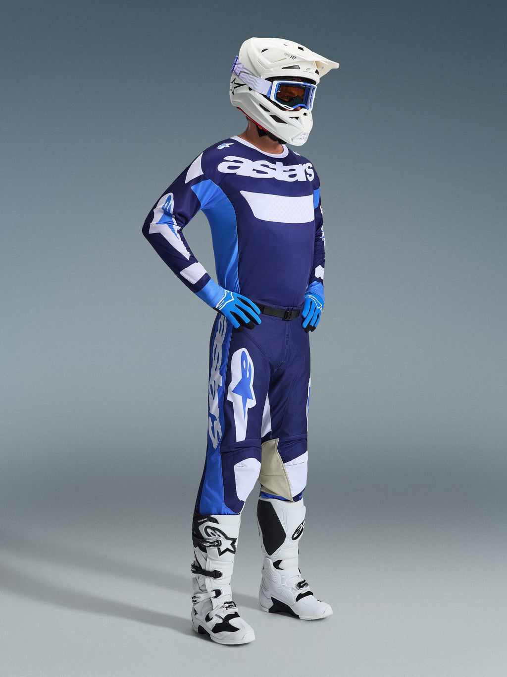 Maglia Alpinestars Racer Riway 2026 in blu Ucla e bianco, indossata da un pilota di motocross con pantaloni coordinati, casco bianco, guanti blu e stivali bianchi, con il marchio 'astars' sul petto, completo da gara off-road