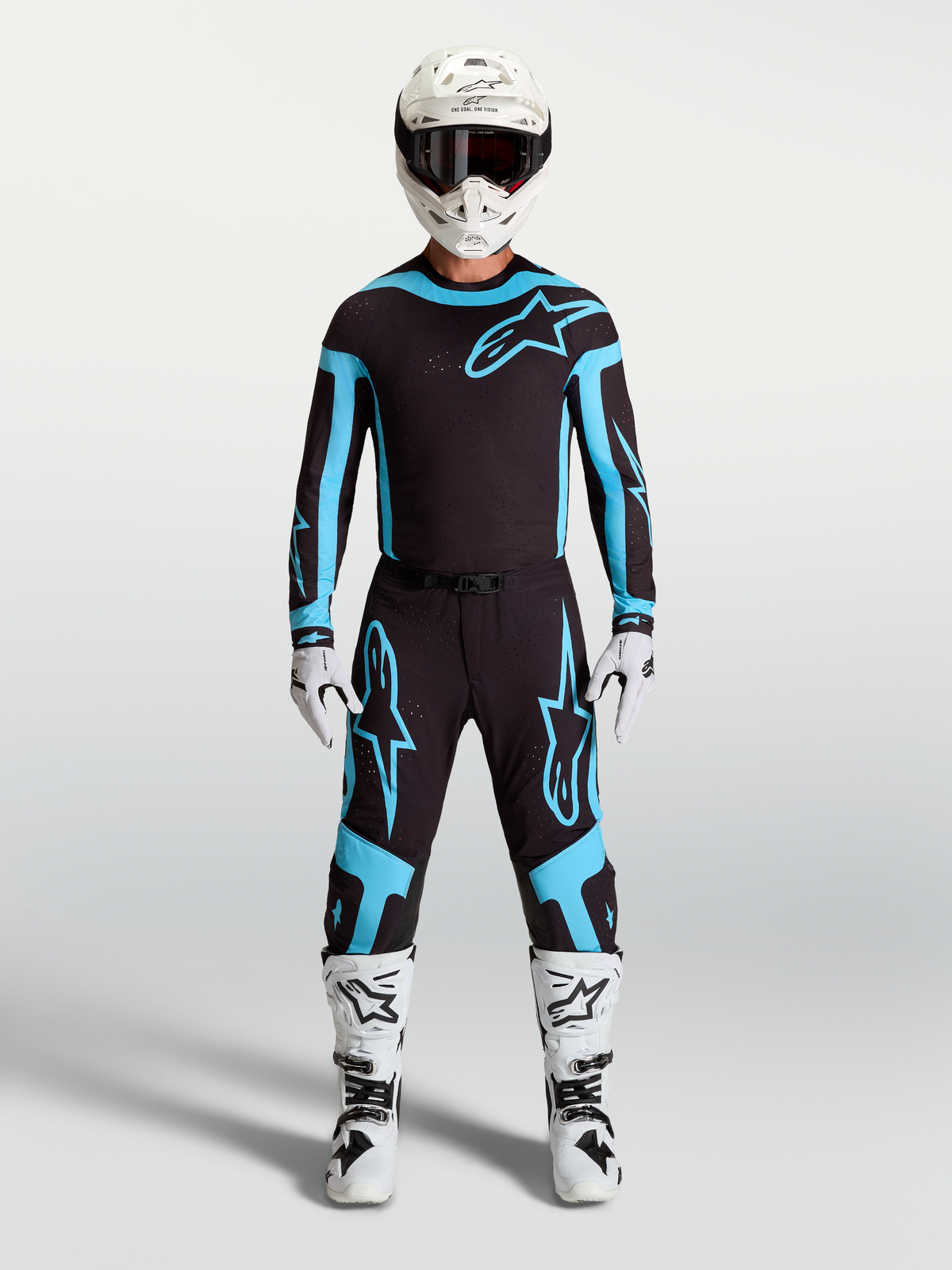 Alpinestars Maglia e Completo Gear Set Supertech Vesta, completo motocross uomo, nero e turchese con stivali e casco bianchi.