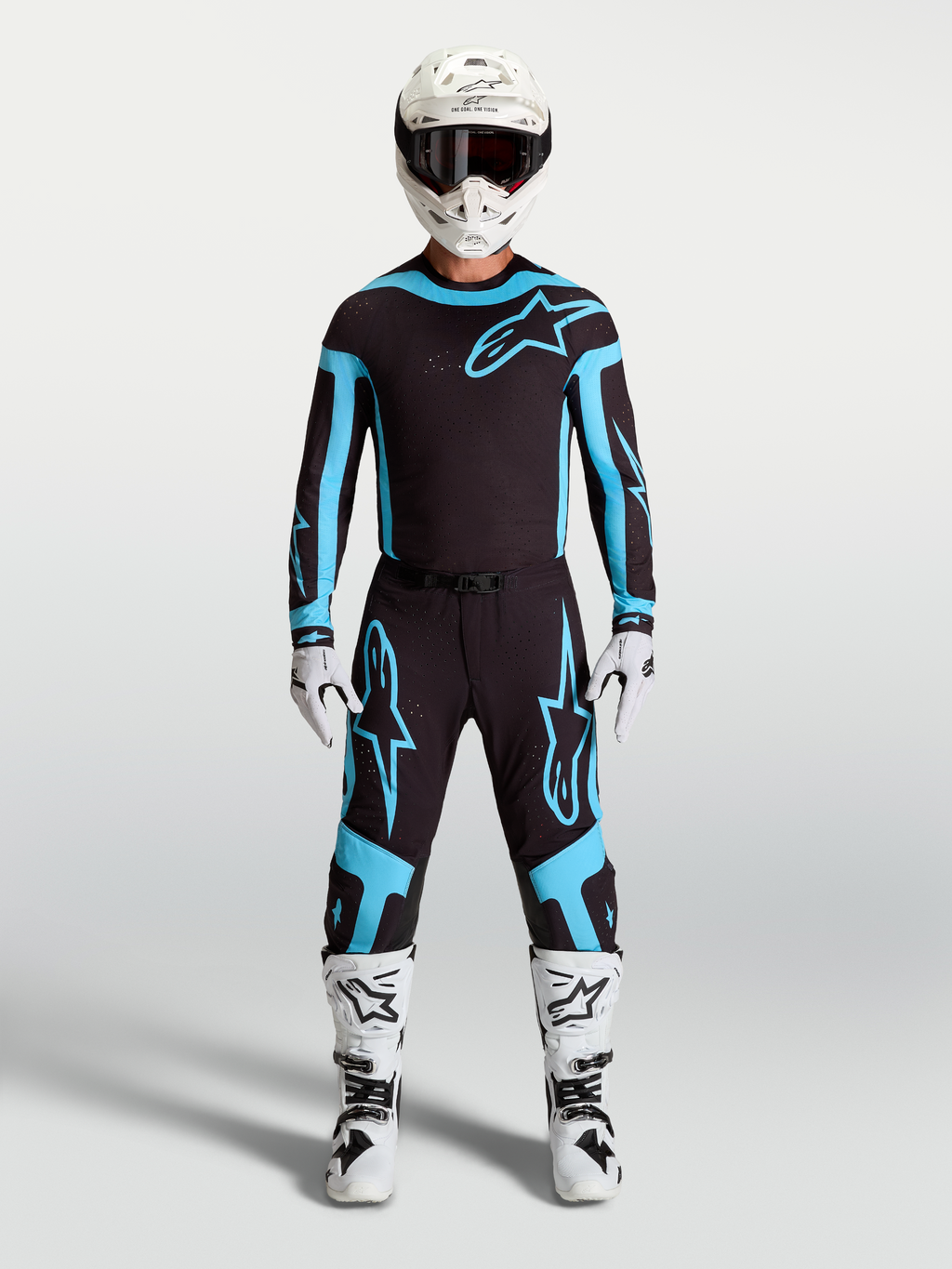 Alpinestars Maglia e Completo Gear Set Supertech Vesta, completo motocross uomo, nero e turchese con stivali e casco bianchi.