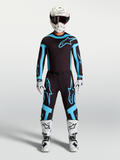 Alpinestars Maglia e Completo Gear Set Supertech Vesta, completo motocross uomo, nero e turchese con stivali e casco bianchi.