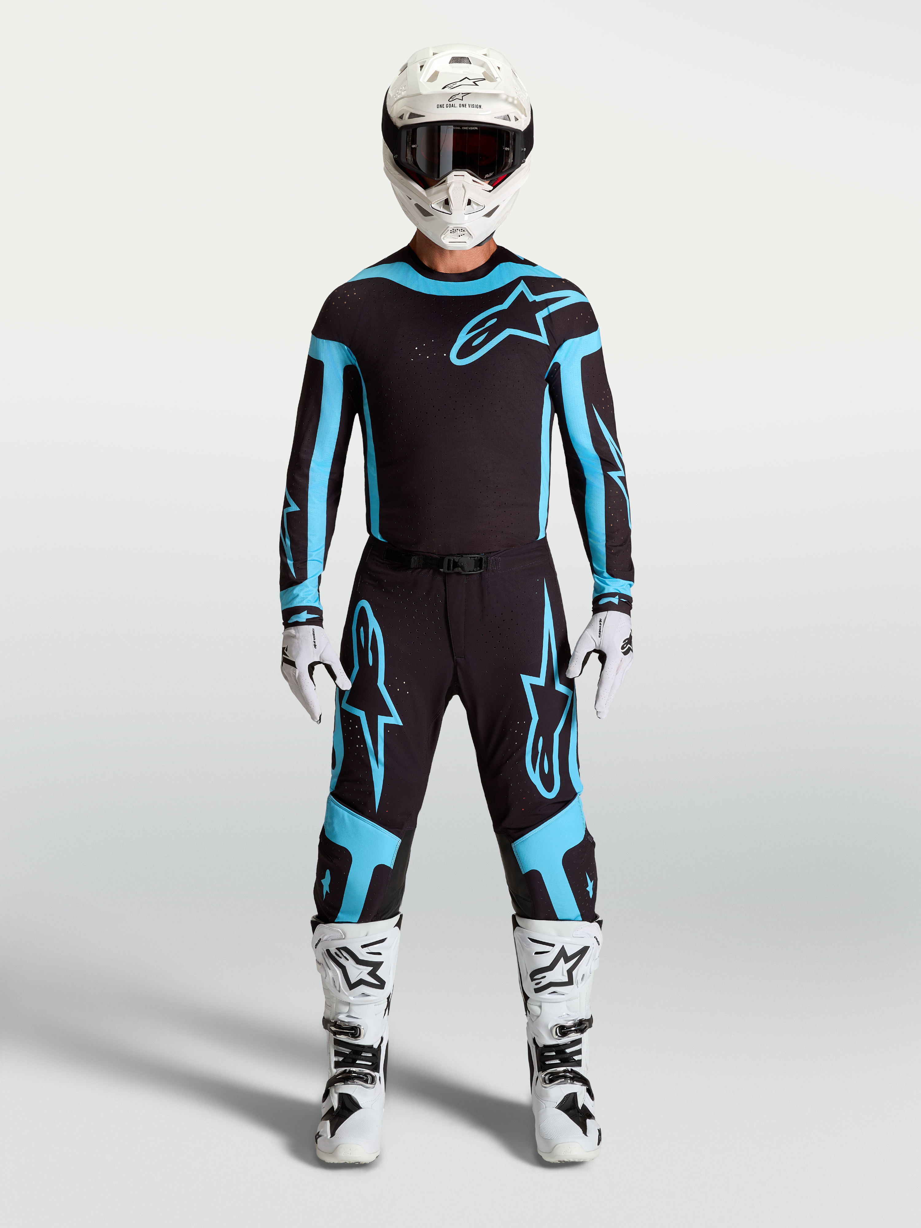 Alpinestars Maglia e Completo Gear Set Supertech Vesta, completo motocross uomo, nero e turchese con stivali e casco bianchi.