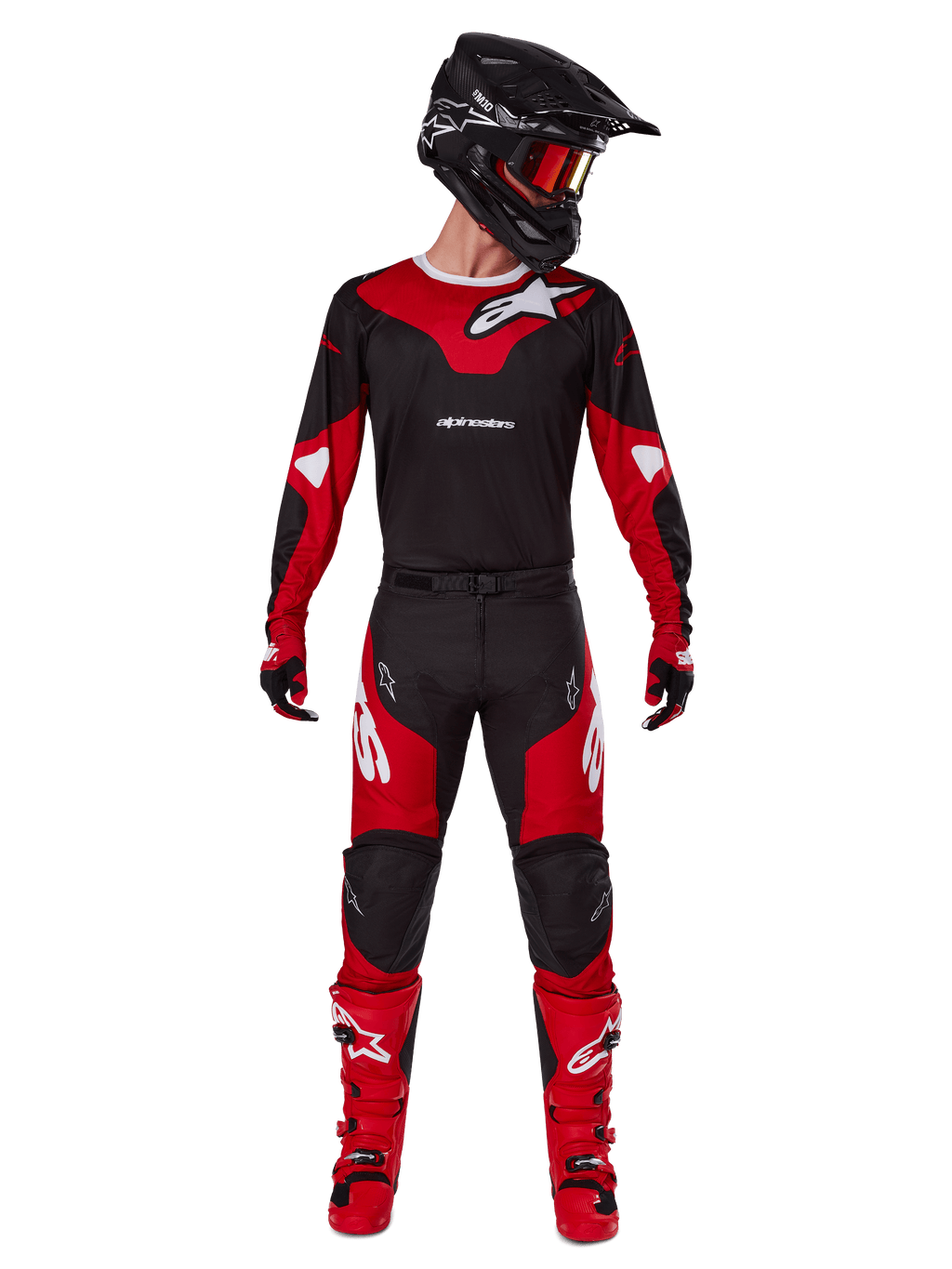 Pilota di motocross che indossa il completo Alpinestars Racer Veil 2025, maglia nera e rosso acceso con logo Alpinestars bianco, pantaloni coordinati, casco nero con occhiali rossi e stivali rossi, outfit completo per la guida fuoristrada