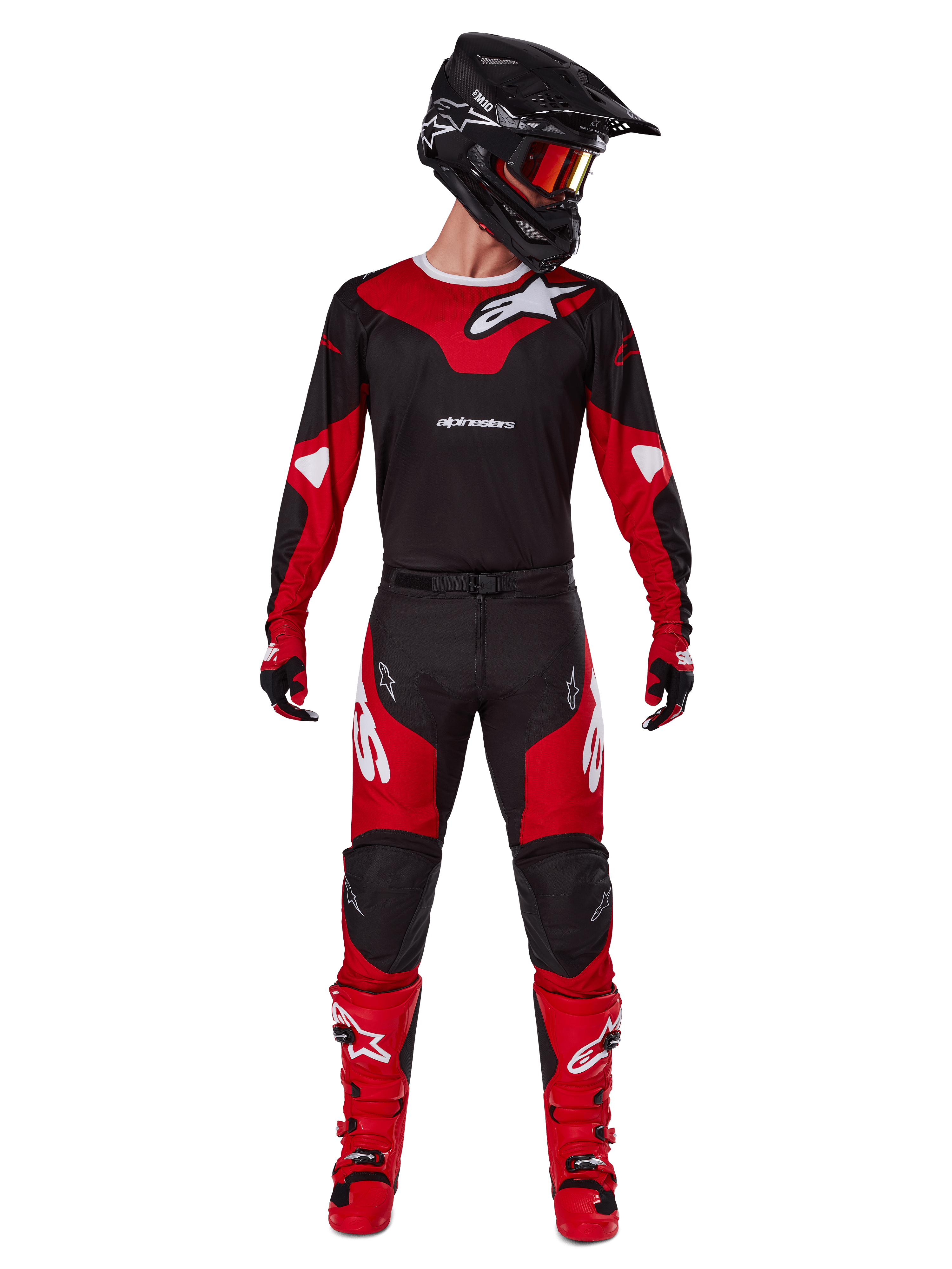 Pilota di motocross che indossa il completo Alpinestars Racer Veil 2025, maglia nera e rosso acceso con logo Alpinestars bianco, pantaloni coordinati, casco nero con occhiali rossi e stivali rossi, outfit completo per la guida fuoristrada