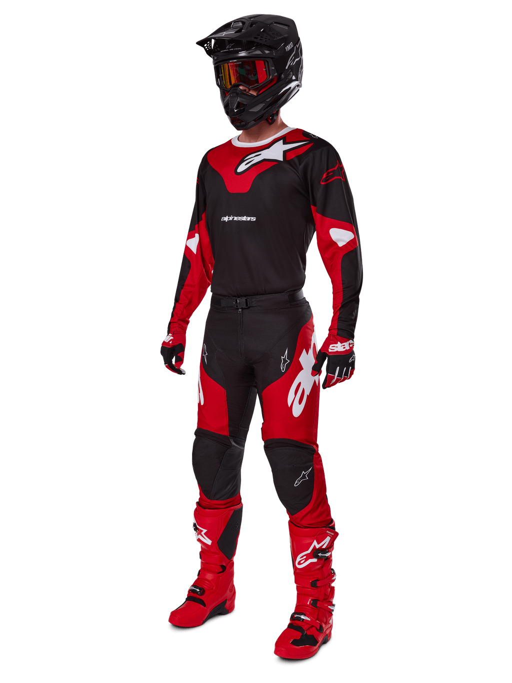 Pilota di motocross con abbigliamento completo da gara Alpinestars, maglia Racer Veil 2025 in nero e rosso brillante, pantaloni coordinati, stivali rossi, casco nero con occhiali rossi e guanti rossi e neri, look tecnico coordinato per gare fuoristrada