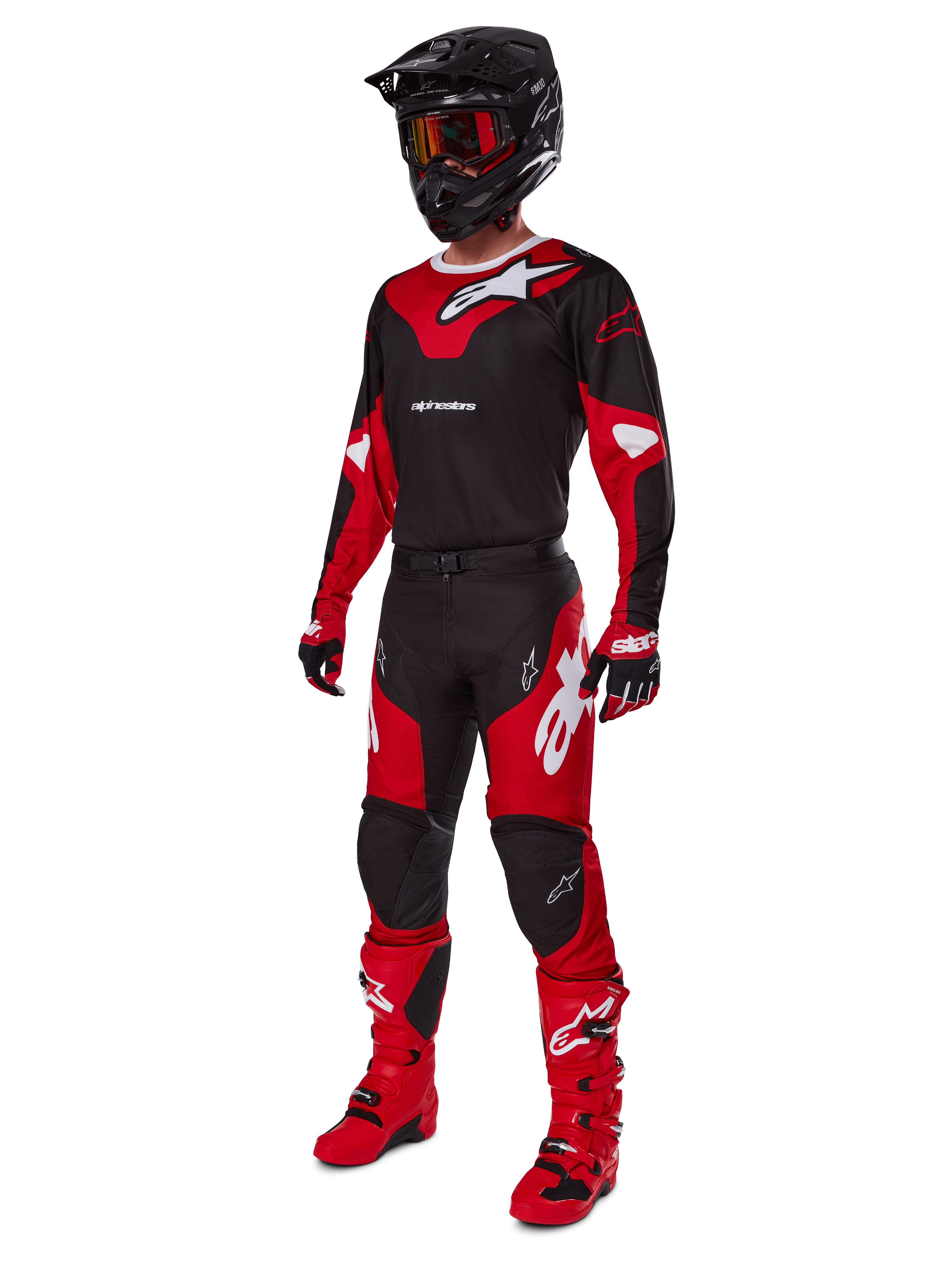 Pilota di motocross con abbigliamento completo da gara Alpinestars, maglia Racer Veil 2025 in nero e rosso brillante, pantaloni coordinati, stivali rossi, casco nero con occhiali rossi e guanti rossi e neri, look tecnico coordinato per gare fuoristrada