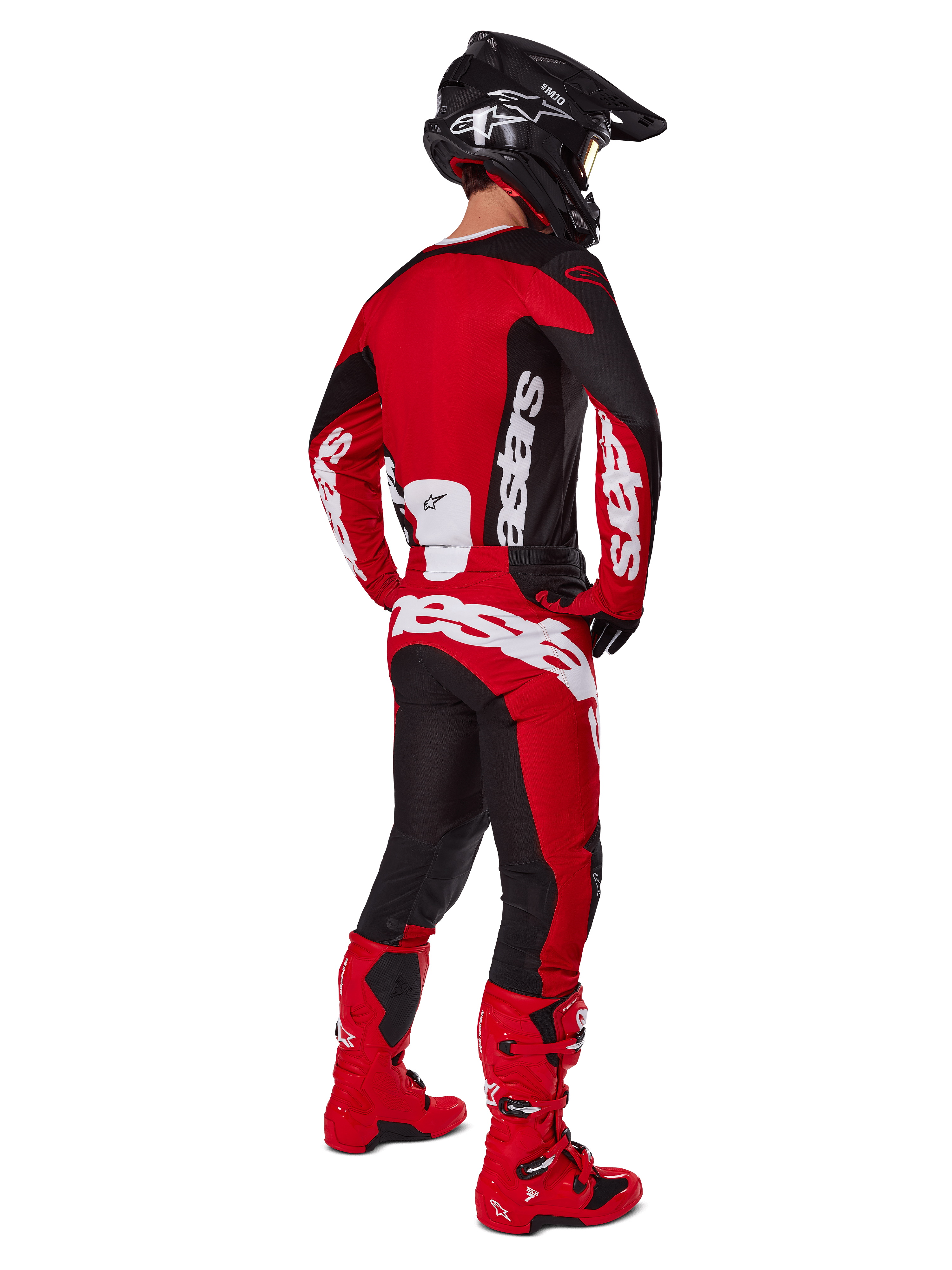 Pilota di motocross di spalle con maglia Alpinestars Racer Veil 2025 in nero e rosso vivace, pantaloni coordinati rossi e neri e stivali rossi, grandi loghi bianchi, ideale per prestazioni off-road