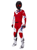 Set completo Alpinestars Racer Veil 2025, abbigliamento da motocross, rosso acceso e bianco con dettagli del logo blu, indossato con casco nero, guanti rossi e stivali bianchi, completo protettivo per prestazioni fuoristrada