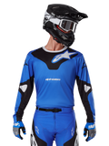 Alpinestars 2025 Racer Veil Jersey, maglia da motocross blu e nera, indossata con attrezzatura da motocross coordinata inclusi casco e guanti, design sportivo con marchio Alpinestars bianco