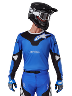Alpinestars 2025 Racer Veil Jersey, maglia da motocross blu e nera, indossata con attrezzatura da motocross coordinata inclusi casco e guanti, design sportivo con marchio Alpinestars bianco