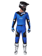 Pilota di motocross con set Alpinestars 2025 Racer Veil Gear, maglia blu e nera con pantaloni abbinati, casco nero con occhiali bianchi, stivali bianchi e neri, abbigliamento da gara coordinato per motocross fuoristrada