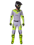 Pilota di motocross con set completo Alpinestars Racer Veil 2025 in grigio e giallo fluo, maglia leggera e pantaloni coordinati, casco nero, occhiali fluo, guanti e stivali giallo alta visibilità, outfit professionale da fuoristrada