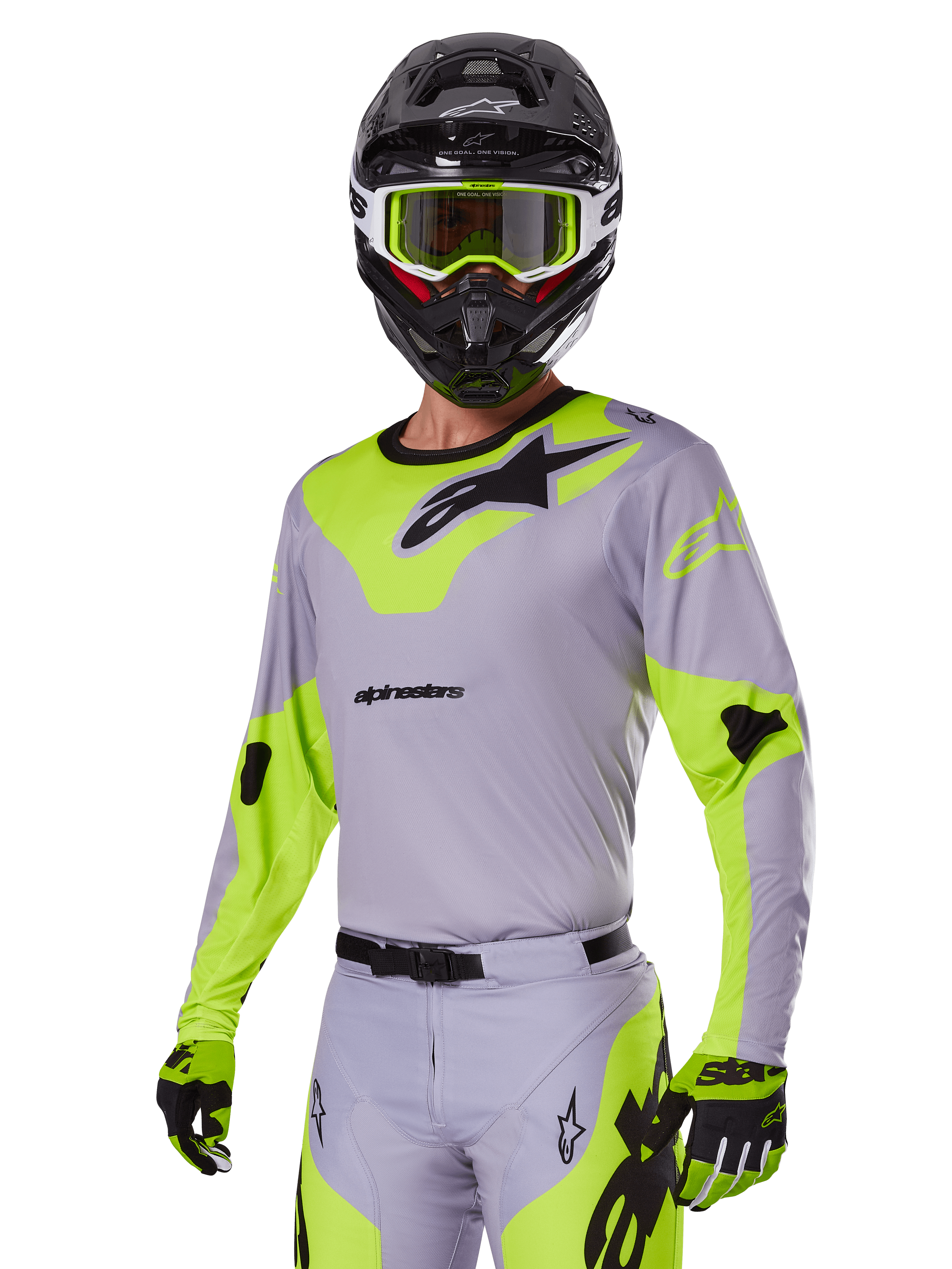 Pilota di motocross con set completo Alpinestars Racer Veil 2025 grigio e verde fluo, maglia e pantaloni grigio chiaro con pannelli giallo-verde neon e loghi neri, guanti abbinati, casco nero con occhiali verde neon, abbigliamento professionale da gara fuoristrada