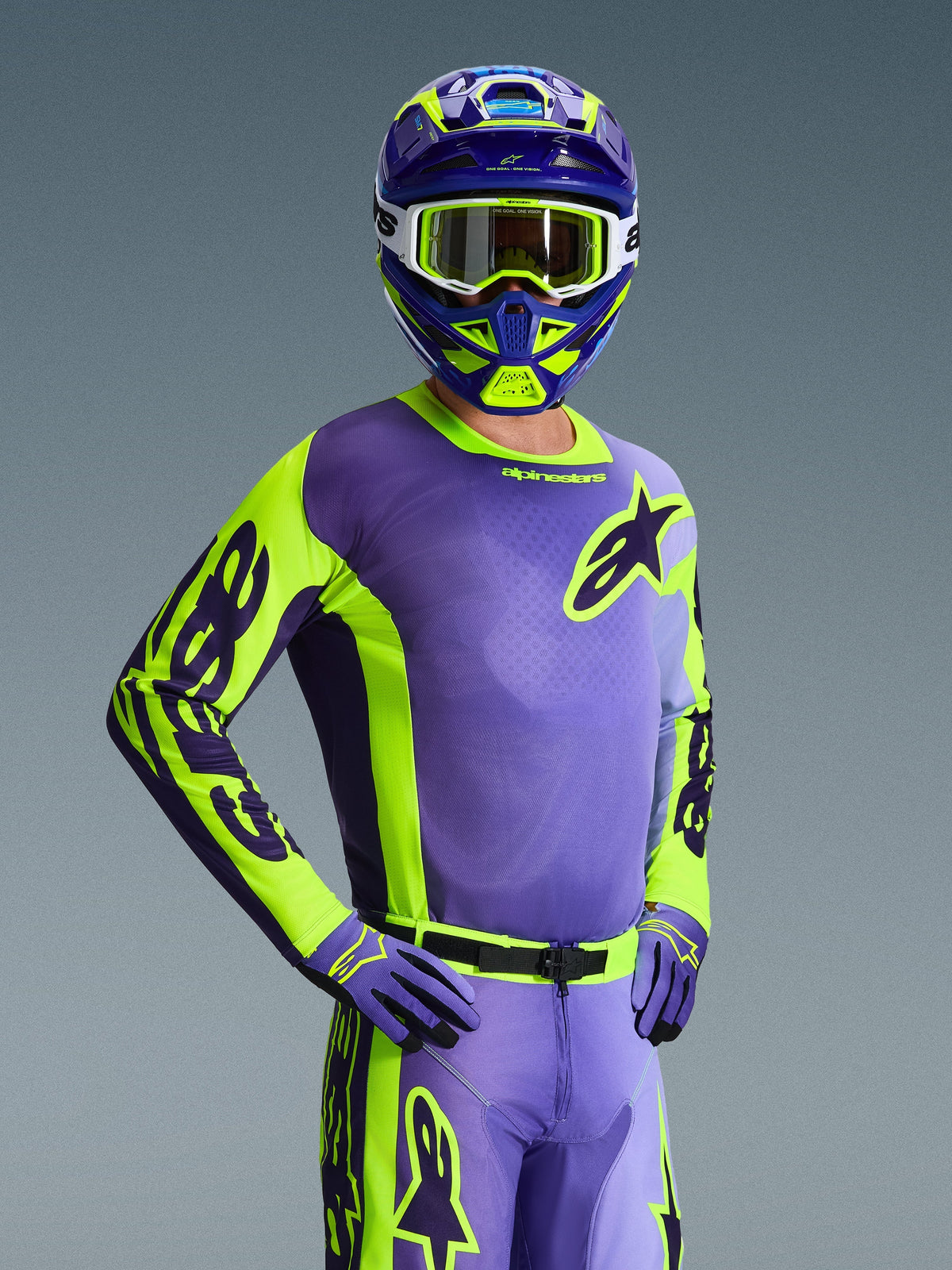 Pilota di motocross con Maglia Racer Portl 2026, viola e giallo fluo, casco coordinato viola e giallo con maschera bianca, guanti viola e giallo, completo da gara coordinato per fuoristrada