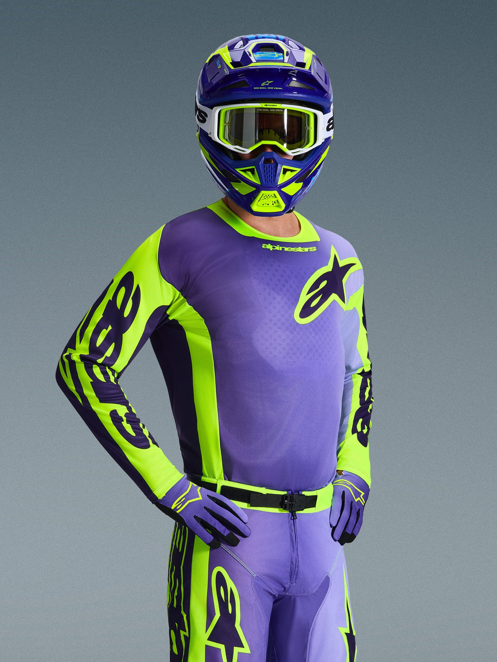 Pilota di motocross con Maglia Racer Portl 2026, viola e giallo fluo, casco coordinato viola e giallo con maschera bianca, guanti viola e giallo, completo da gara coordinato per fuoristrada