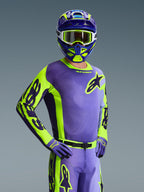 Pilota di motocross con Maglia Racer Portl 2026, viola e giallo fluo, casco coordinato viola e giallo con maschera bianca, guanti viola e giallo, completo da gara coordinato per fuoristrada