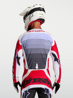 Alpinestars maglia Techstar Maven, maglia da motocross uomo rosso fuoco e bianca, traspirante, vista posteriore su pilota.