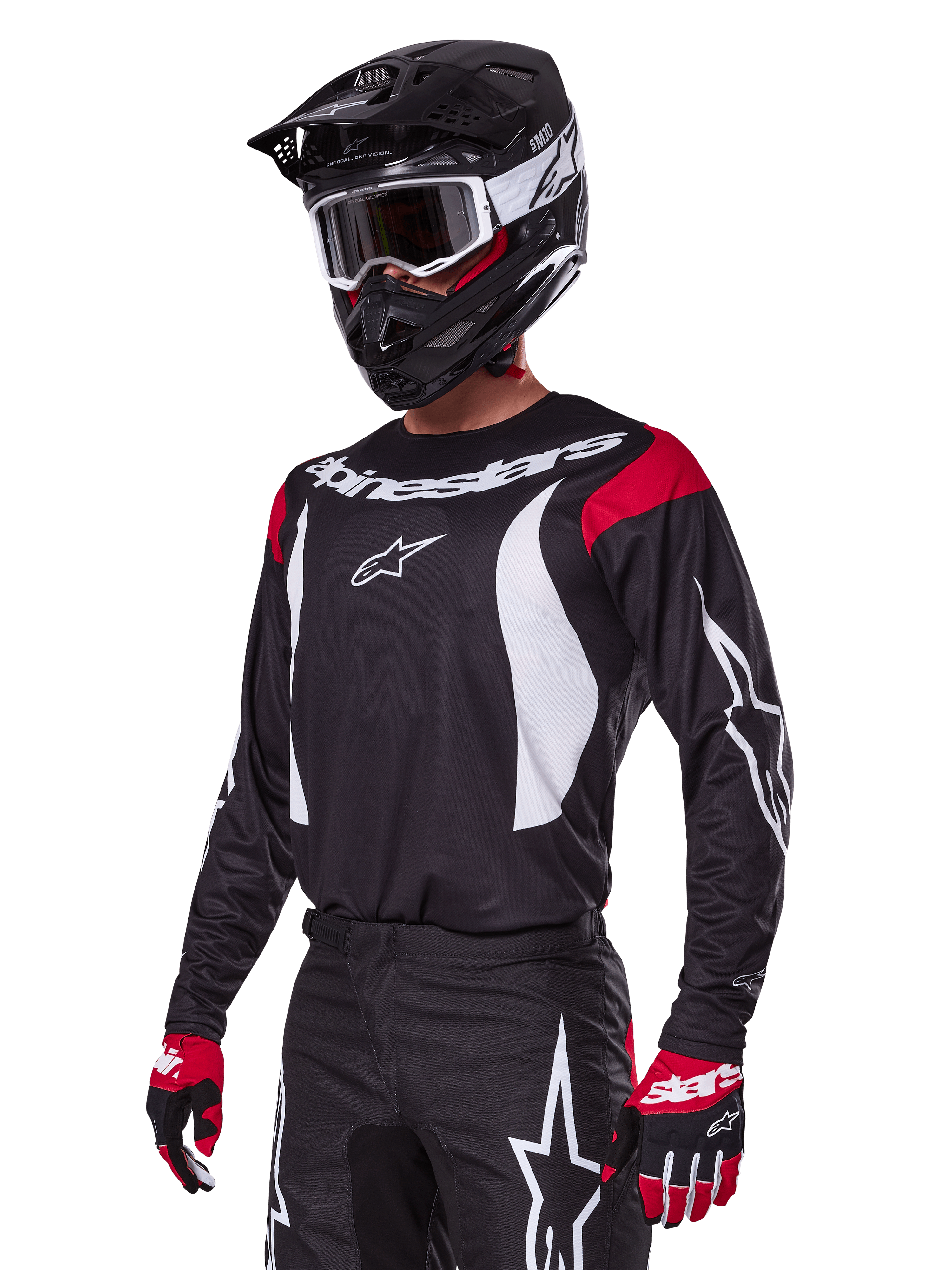 Pilota di motocross che indossa il set Alpinestars 2025 Fluid Haul, maglia nera con pannelli rossi sulle spalle e grafiche bianche, pantaloni neri coordinati con loghi a stella bianchi, guanti rossi e neri, casco nero con dettagli bianchi e occhiali, abbigliamento da motocross coordinato.