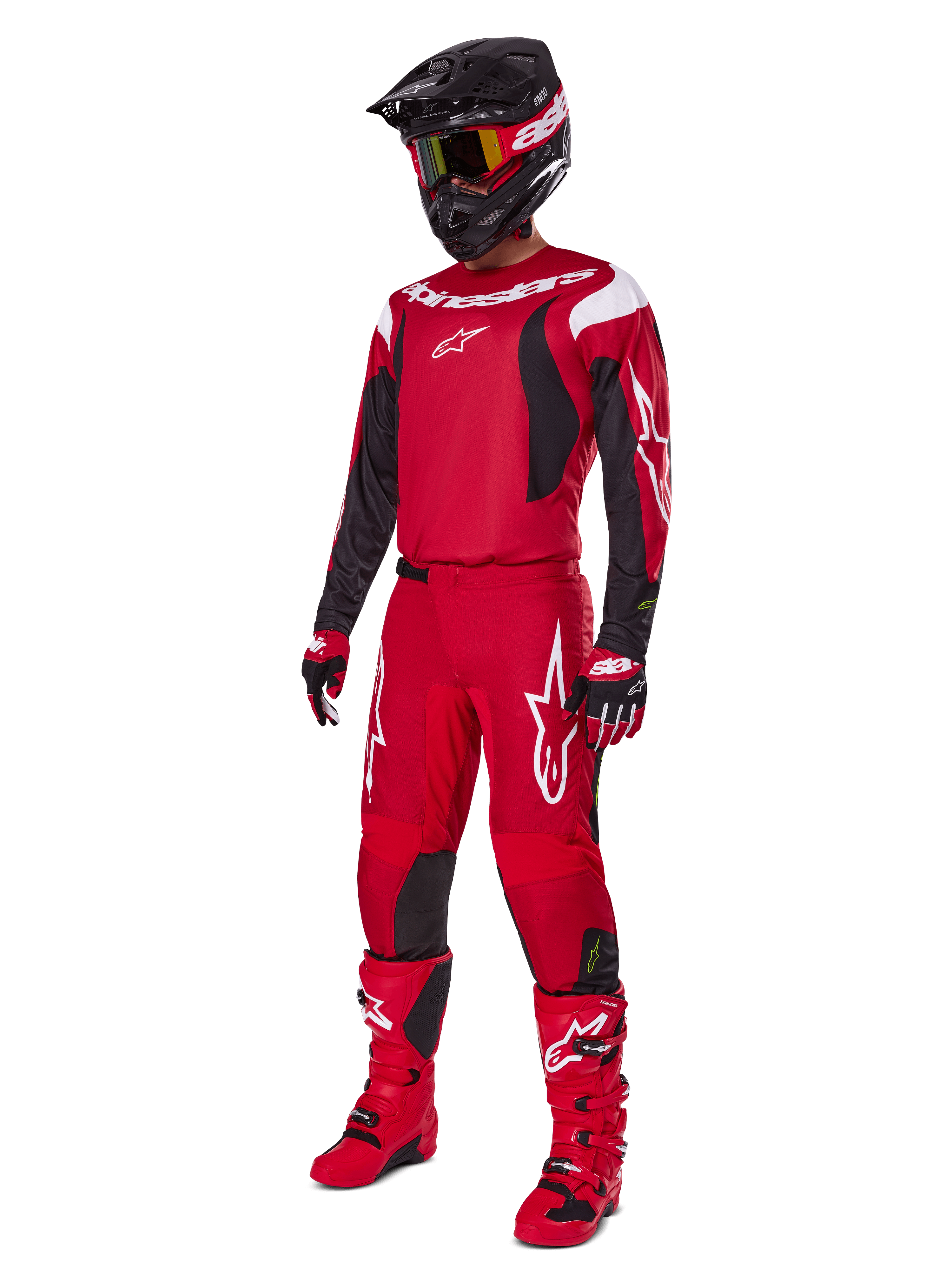 Pilota di motocross che indossa il set Alpinestars 2025 Fluid Haul, rosso brillante con accenti neri e bianchi, completo di maglia, pantaloni, casco, stivali e guanti, progettato per prestazioni e protezione fuoristrada